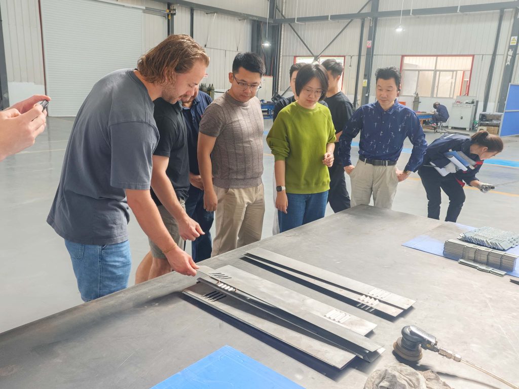 U.S. customer and STARWAY team members reviewing manufactured sheet metal components on a workshop table